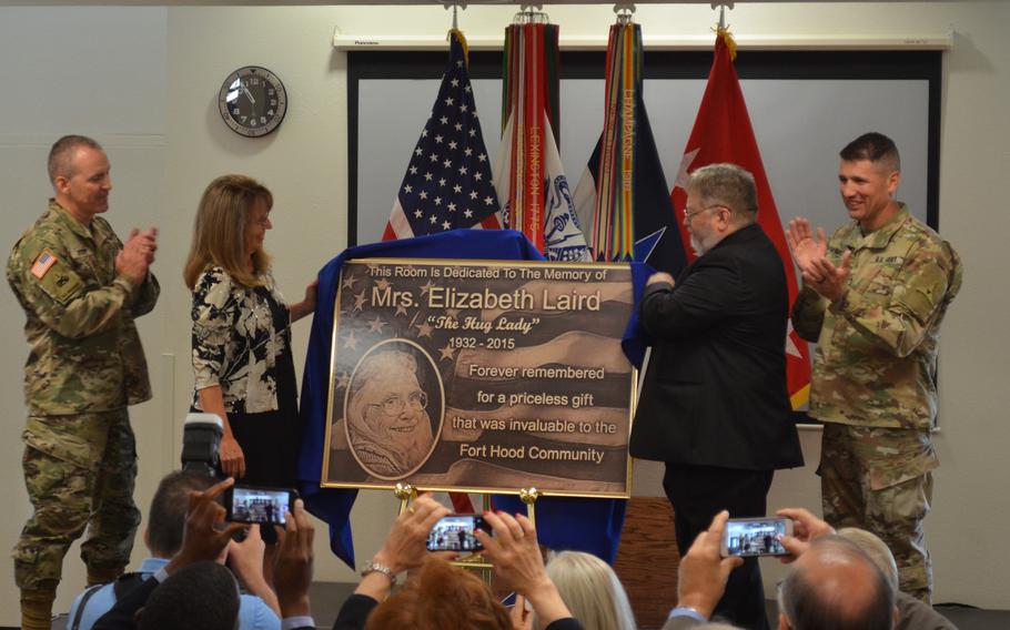 Susan Dewees-Taylor and Richard Dewees unveil a replica of a plaque to honor their mother Elizabeth Laird, the "Hug Lady," during a ceremony in Laird's honor July 1, 2019 at Robert Gray Army Airfield at Fort Hood, Texas. They are joined by the Fort Hood command team, Lt. Gen. Robert P. White and Command Sgt. Maj. Daniel Hendrex. 