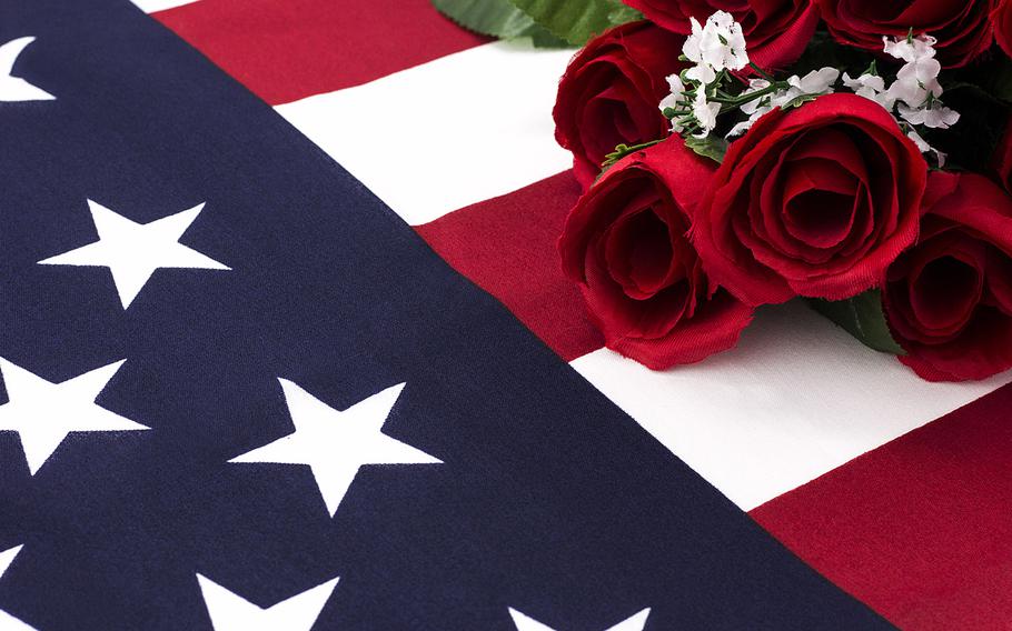 Close shot of roses laying on top and wrapped in American flag