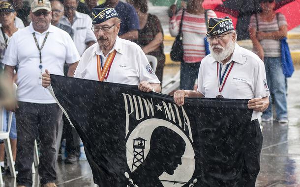 Korean War Army veteran Rafael Gomez and Vietnam veteran Javier Morales present the Prisoner-of-War-Missing-in-Action flag during a down-pour at the start of a Veteran Day celebration event in Catano, Puerto Rico, on Saturday, Nov. 11, 2017.