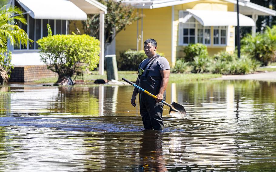 A Seminole County firefighter works to clear a drain at an intersection in Hacienda Village, a 55-plus manufactured homes community in Winter Springs, Florida, on Sunday, Oct. 2, 2022. 