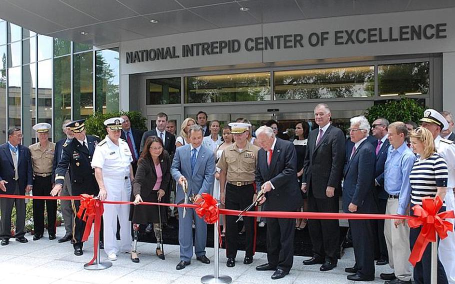 Arnold Fisher, right, the honorary chairman of the Intrepid Heroes Fund, cuts the ribbon at the grand opening Thursday of the National Intrepid Center of Excellence on the campus of the National Naval Medical Center in Bethesda. The Center will provide treatment for severe cases of traumatic brain injury and post-traumatic stress disorder.
