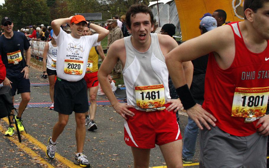 Finishers catch their breath after crossing the finish line at the Marine Corps Marathon on Oct. 28, 2012.