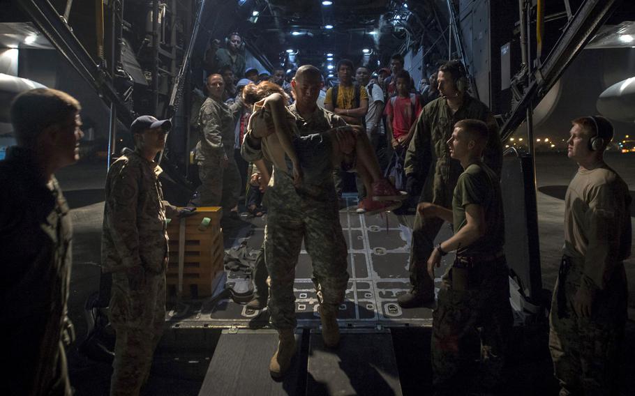 Sgt. 1st Class Faamasino Galoia, assigned to Joint Special Operations Task Force Philippines, carries a Filipino girl off a MC-130 Combat Talon II from 1st Special Operation Squadron she was transported from Ormac to Manila as part of Operation Damayan relief efforts on Nov. 21, 2013. The Philippine government closely coordinated relief efforts, including search and rescue, supply drops and personnel airlifts, with military and civilian organizations.
