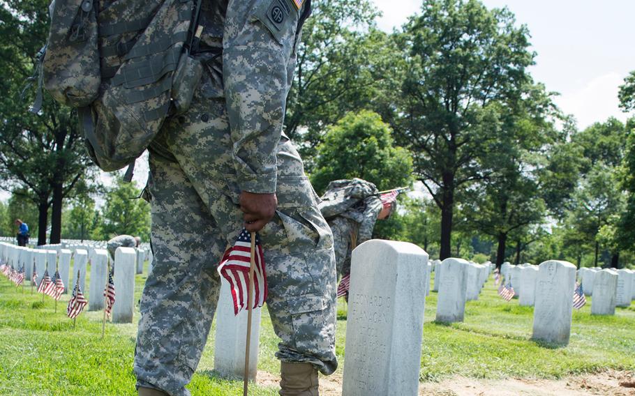 The ritual: Toe of the combat boot placed against the center of a headstone, flag planted at the heel.