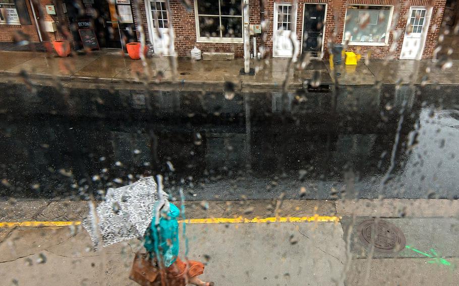 A pedestrian uses an umbrella to take shelter from the rain as they walk down Water Street in Harrisonburg, Va., on April 14, 2015.