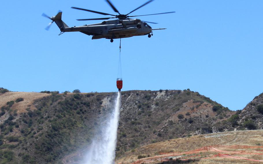 A Marine Corps CH-53 Super Stallion dumps water it collected from Pulgas Lake on nearby land at Camp Pendleton, Calif., Thursday, as part of a wildfire fighting training exercise.