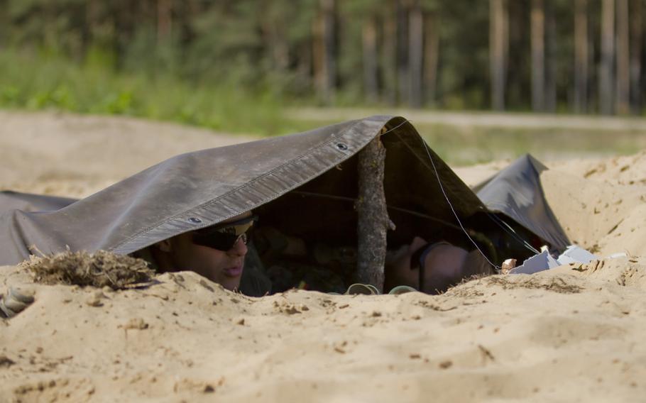 German army soldiers assigned to 5th Company, Jager Battalion as forward observers, hide in their camouflaged foxhole during the second day of multinational training at the Great Lithuanian Hetman Jonusas Radvila Training Regiment, in Rukla, Lithuania, June 11, 2015.