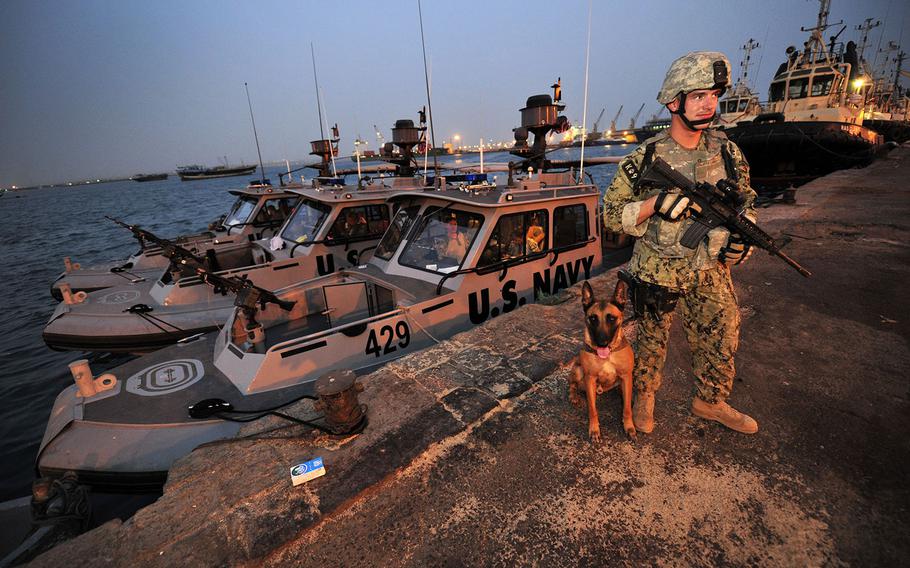 Master-at-Arms 2nd Class John Winjum, a military working dog handler, assigned to Camp Lemonnier, Djibouti security forces, stands duty at the Port of Djibouti during an inspection of ships, tugboats and the pier on July 7, 2014.