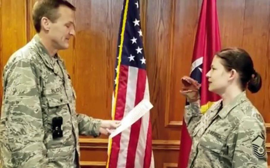 A screenshot from a video of an Air National Guard master sergeant using a dinosaur hand puppet while reciting the oath of re-enlistment.