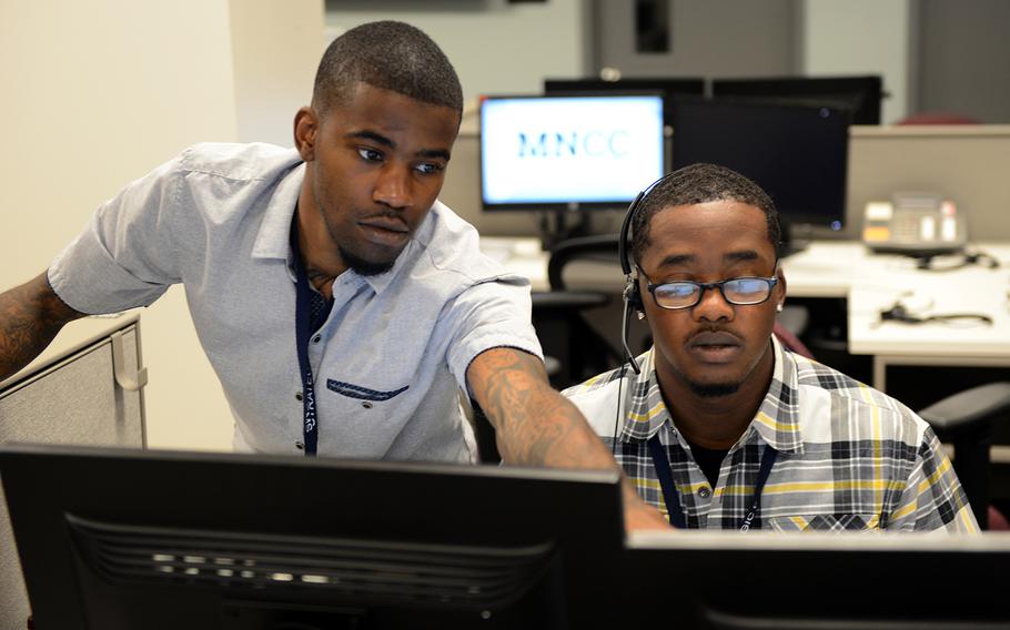 A supervisor helps a customer service agent with a call at the MyNavy Career Center at Navy Personnel Command in Millington, Tenn.