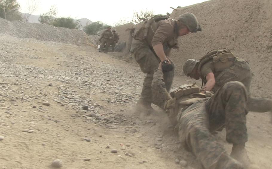 In a still from ''Combat Obscura,'' a film that uses footage shot in Afghanistan by a Marine, two marines help a fellow servicemember wounded in a firefight in Helmand province sometime during their 2011 to 2012 deployment.
