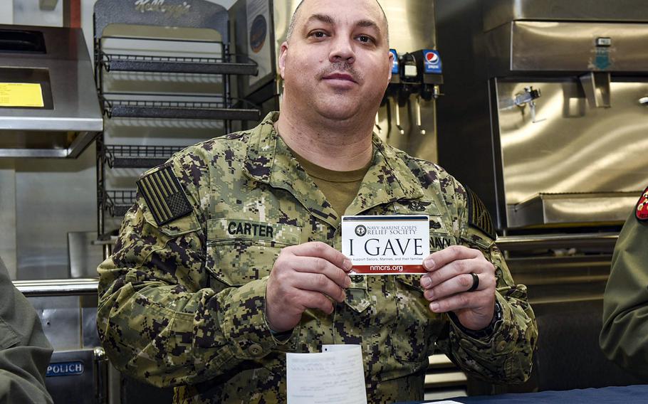 Command Master Chief Jonas Carter poses after donating to the Navy and Marine Corps Relief Society aboard the USS Harry S. Truman in Norfolk, Va., Feb. 28, 2019.