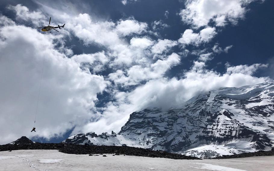 A Mt. Rainier National Park Service rescue helicopter transfers an injured climber from an accident site at 10,400 feet on Liberty Ridge to a staging area on the north side of Mount Rainier, May 30, 2019. Bill Dean, a former special operations soldier instrumental in the fight against the Islamic State group, died recently during a climb along the ridge.