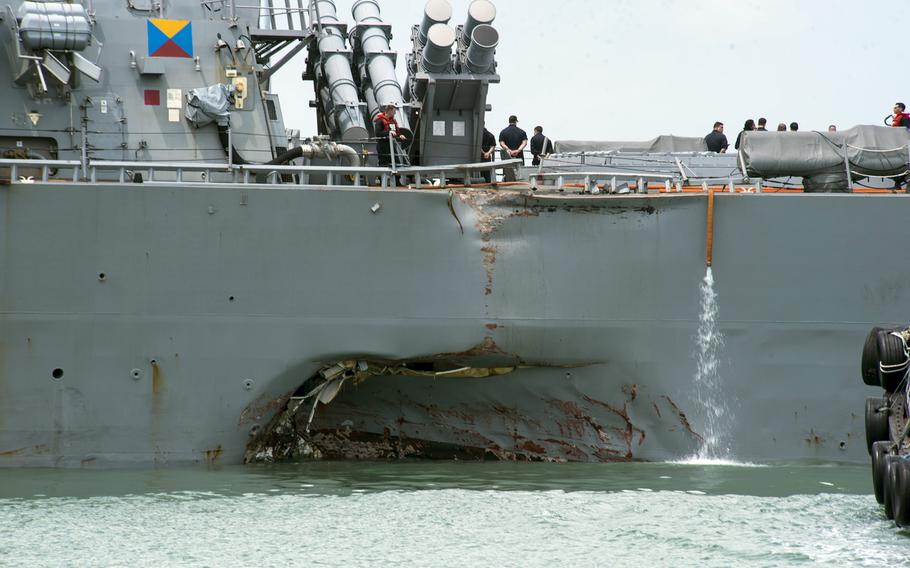 Damage to the left side is visible as the destroyer USS John S. McCain steers towards Changi Naval Base, Singapore, following a collision with a merchant vessel on Aug. 21, 2017. The Navy is replacing touch-screen throttles and helms on destroyers with hand-held ones after determining that the McCain's controls caused confusion that contributed to the collision.