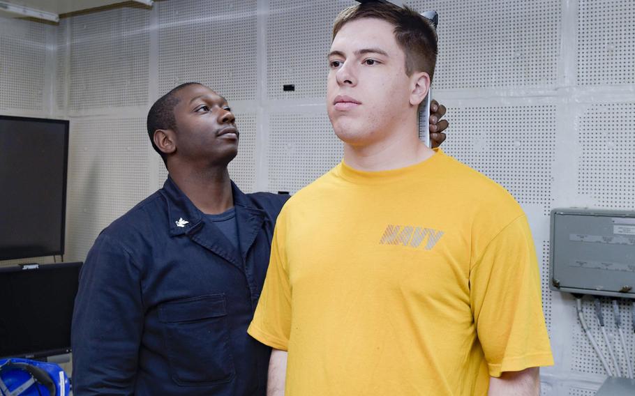 Petty Officer 2nd Class Byron Cary measures the height of Seaman Joshua Ritchie, during the body composition assessment aboard the aircraft carrier USS Dwight D. Eisenhower in 2017. The Marines were the leanest service last year, whereas the Navy was the fattest, according to a Pentagon study.