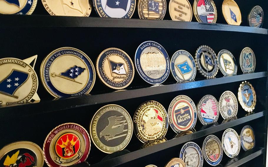 A display case features command and flag officer coins. The origin of commanders presenting coins to deserving sailors is disputed, but some historians think the tradition in U.S. history stems from the U.S. Civil War.