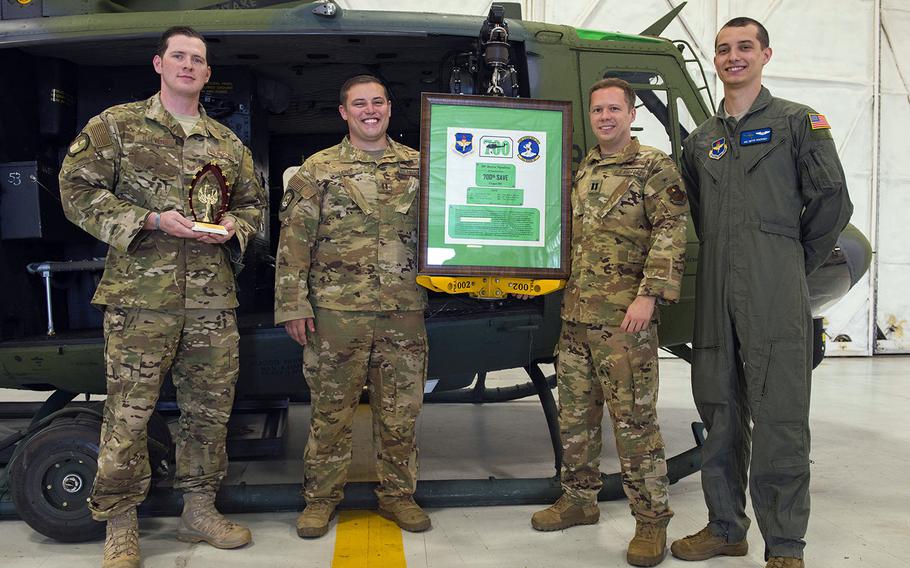 Members of the 36th Rescue Squadron pose with a plaque commemorating 700 saves at Fairchild Air Force Base, Wash., Sept. 20, 2019.