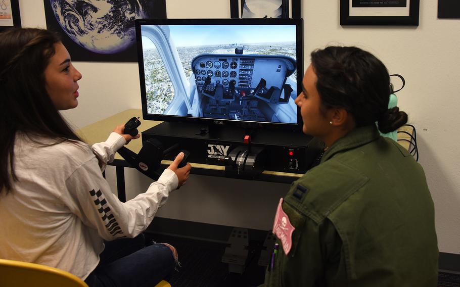 An Air Force women's fly-in participant guides a young woman through a virtual reality flight simulator during the Girls in Aviation Day event hosted by the North Texas Chapter of Women in Aviation International at the Frontiers of Flight Museum in Dallas, Texas, Sept. 21, 2019.