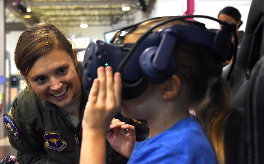 An Air Force women's fly-in participant guides a girl through a flight simulator at the Girls in Aviation Day event hosted by the North Texas Chapter of Women in Aviation International at the Frontiers of Flight Museum in Dallas, Texas, Sept. 21, 2019.
