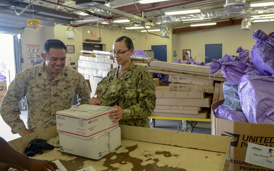 Petty Officer 1st Class Alyssa Babcock, right, signs for department mail at Camp Lemonnier, Djibouti, Dec. 12, 2019. A new U.S. Postal Service policy would require everyone, including those at overseas military post offices, to fill out and print electronic customs forms, which military officials say is likely to cause customer delays.