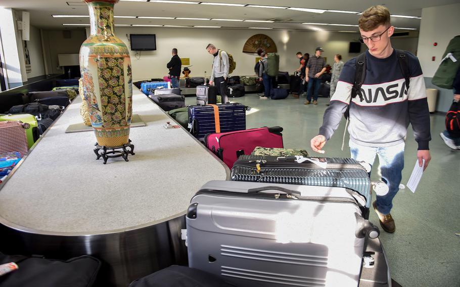 A Patriot Express flyer retrieves his luggage inside the passenger terminal at Yokota Air Base, Japan, Nov. 28, 2018.