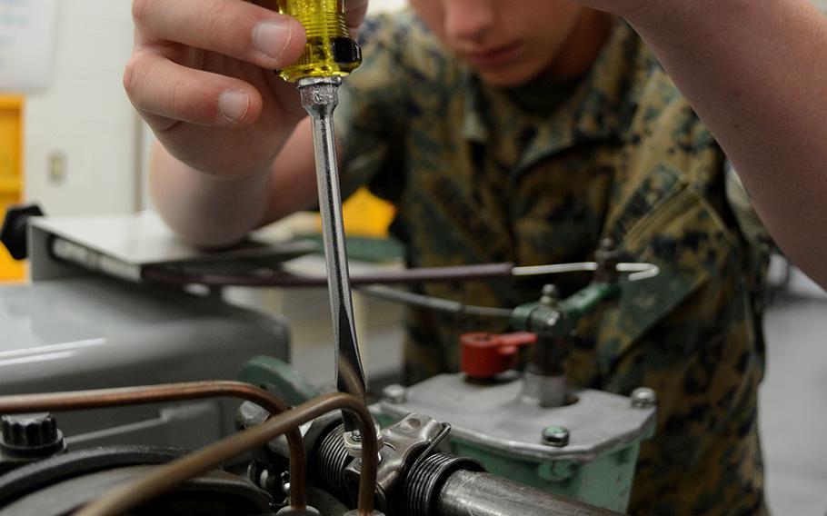 A Marine adjusts the fuel control rack assembly on an engine training aid during a class at Naval Air Technical Training Center at Naval Air Station Pensacola, Fla., in 2017.