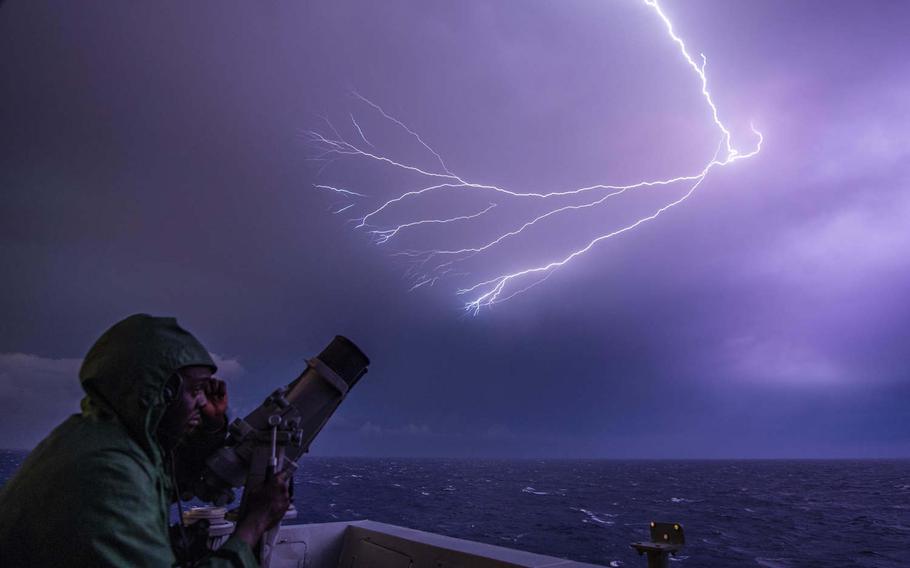 Seaman Rakeem Williams, of Goldsboro, N.C., stands watch during a lightning storm aboard the amphibious transport dock ship USS John P. Murtha on Nov. 18, 2019. This photo was part of a portfolio that earned Petty Officer 2nd Class Kyle Carlstrom honors as the Defense Media Activity's military photographer of the year for 2019.