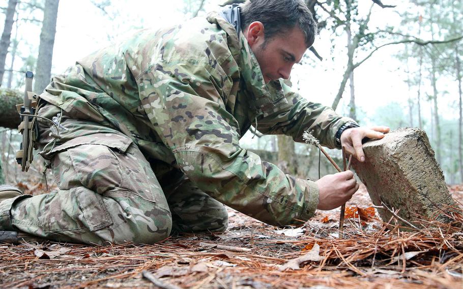 A student from the U.S. Army John F. Kennedy Special Warfare Center and School practices setting a trap for small game during the survival phase of Survival, Evasion, Resistance and Escape Level-C training at Camp Mackall, N.C., in February 2019. More than 100 troops participating in the present course have been quarantined this week, after most of them tested positive for COVID-19.