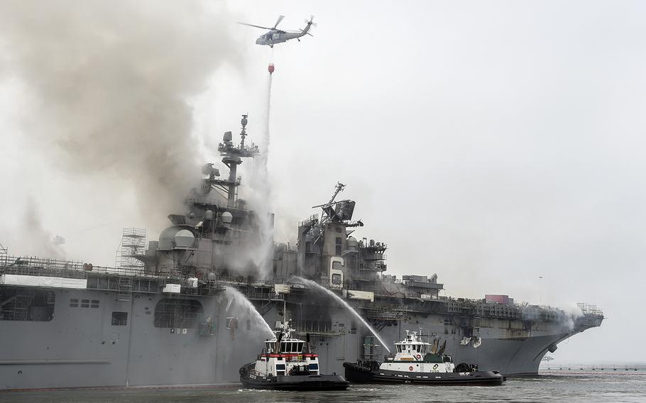 Firefighters and an aircraft from Helicopter Sea Combat Squadron 3 battle a blaze aboard the amphibious assault ship USS Bonhomme Richard at Naval Base San Diego, Calif., Monday, July 13, 2020.