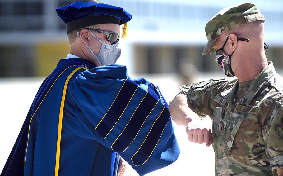 An Air Force Academy cadet bumps elbows with a member of faculty at the academy's first-ever convocation ceremony on Aug. 2, 2020 to mark the beginning of the academic year. Two weeks later, despite the academy taking numerous precautions to stem the spread of the coronavirus, an unspecified number of cadets tested positive for it.