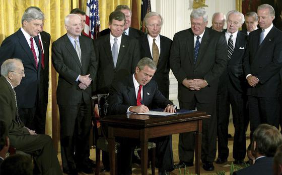 FILE - President George W. Bush signs a resolution authorizing the use of force against Iraq, Oct. 16, 2002, in the East Room of the White House. Left to right, Sen. Jesse Helms, R-N.C., Sen. John Warner, R-Va., Sen. John McCain, R-Ariz., Rep. Roy Blunt, R-Mo., Sen. Joseph Lieberman, D-Conn., Speaker the House Dennis Hastert, R-Ill., Rep. Tom Lantos, D-Calif., Sen. Joseph Biden, D-Del. 