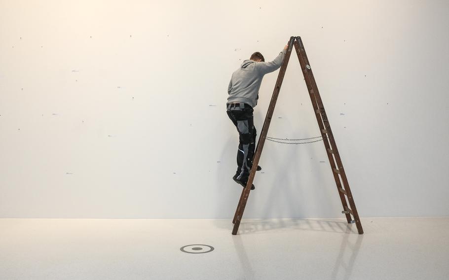 A Leica employee removes hangars as the gallerychanges the photo exhibits at the Leica manufacturing and administrative complex in Wetzlar, Germany, Jan. 6, 2015.

