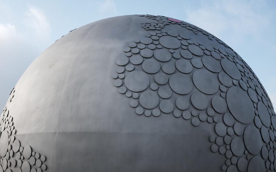 The famous Leica red dot marks Germany at the upper right of the giant metal globe resting in the center of the roundabout outside the entrance to the World of Leica, the Leica manufacturing and administrative complex, in Wetzlar, Germany, Jan. 6, 2015.

