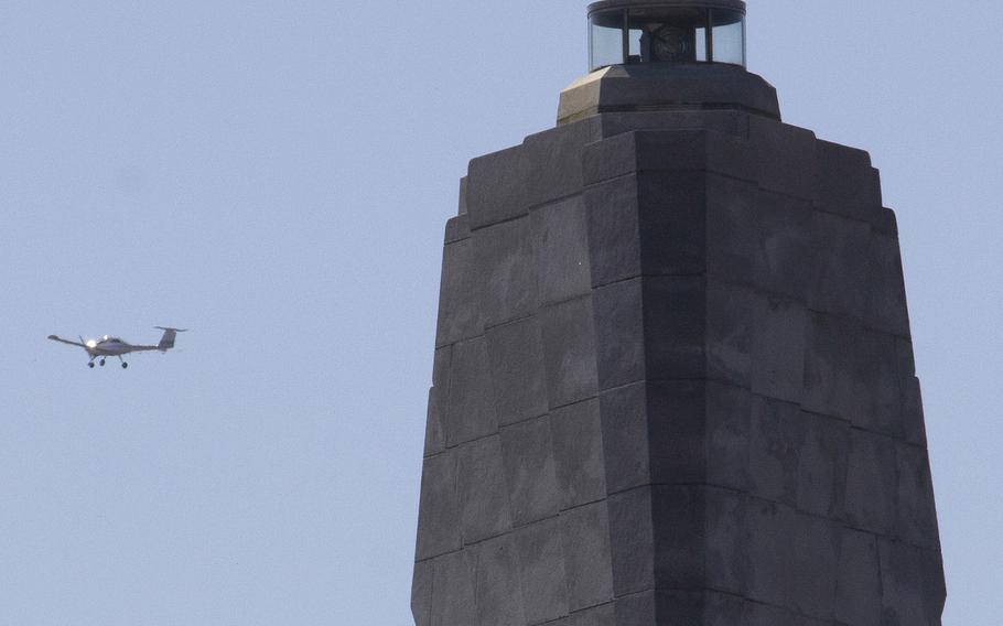 A small plane flies past the Wright Brothers National Memorial in Kitty Hawk, N.C., after taking off from the adjacent airstrip.