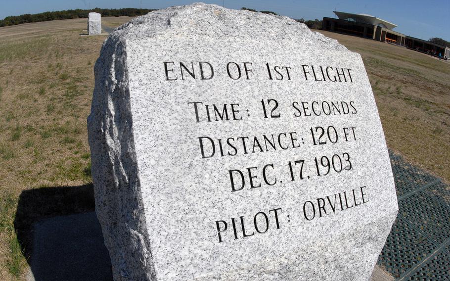 A commemorative stone at the Wright Brothers National Memorial in Kitty Hawk, N.C. In the background are the visitors center on the right and the stone marking the endpoint of the second flight on the left.