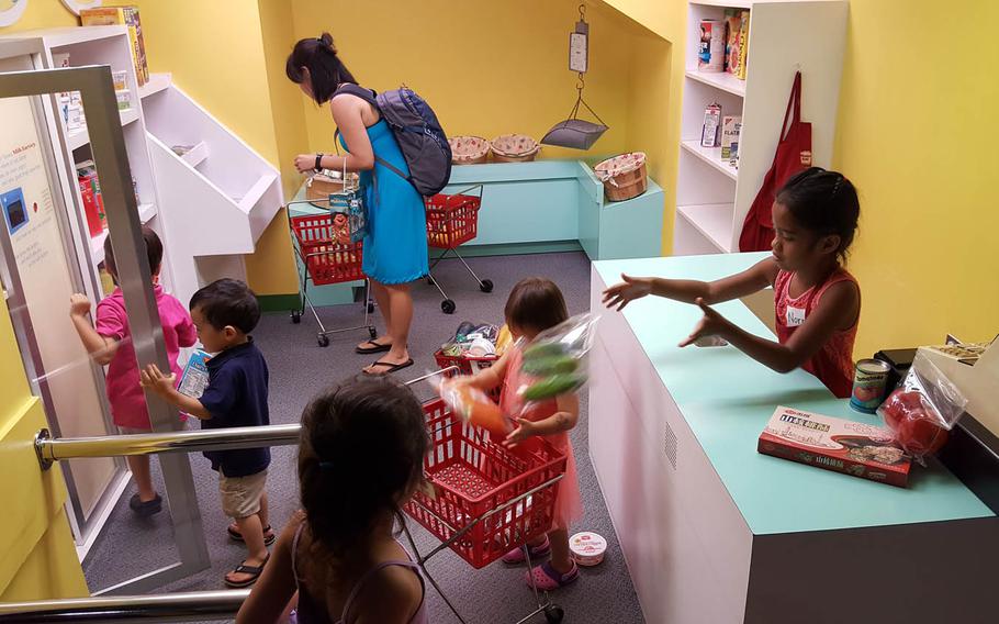 Young grocery shoppers jockey for position at a store in "Your Town," an interactive display at Hawaii Children's Discovery Center in Honolulu.