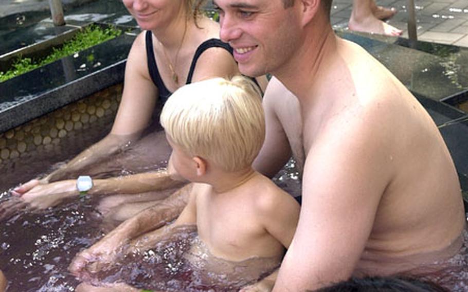 Lt. Cmdr. Trey White, from Atsugi, enjoys one of the vibrating pools with his wife Carla and son Michael at Yunessun.