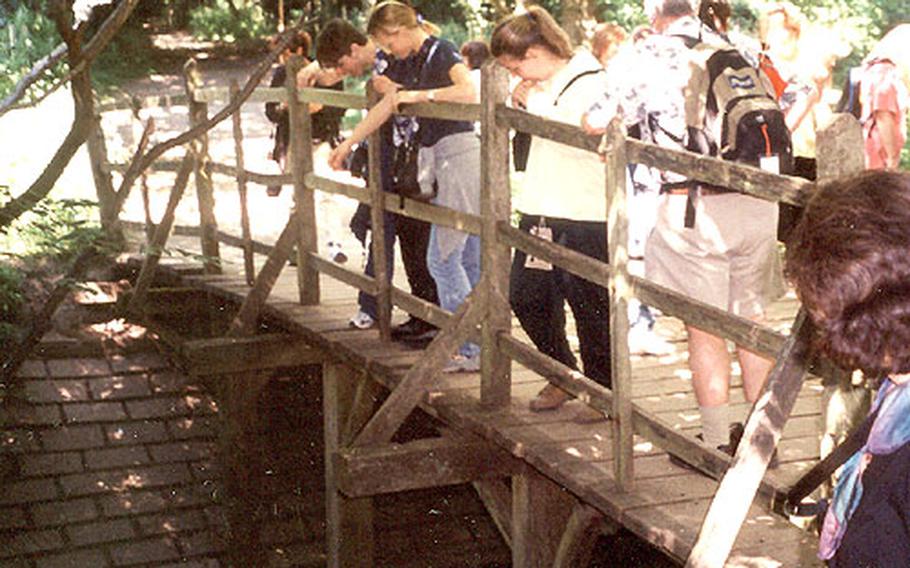 Visitors to the forest watch sticks float downstream as they play Poohsticks at Poohsticks Bridge.