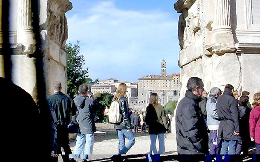 Tourists make their way along-side the Arch of Titus in the Roman Forum. In the distance is Michelangelo’s Piazza del Campanology.