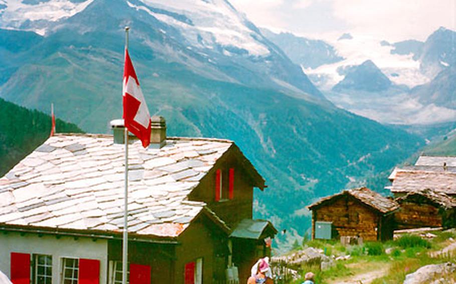 Hikers pass a mountain hut flying the Swiss flag under the mighty Matterhorn. When the weather is good, between 100 and 200 climbers try to ascend the Matterhorn every day. But at any time of year, Zermatt, Switzerland, is known for outdoor activities.