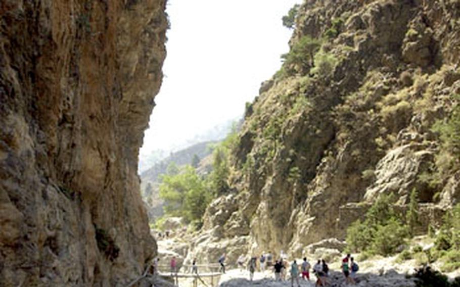 Hikers walk through the narrow valley of the Samaria Gorge.
