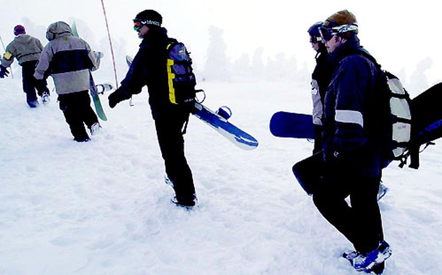 Snowboarders trek from a cable car that brought them to trails near the 4,300 foot level of Mount Tamoyadaki in the Hakkoda Mountains, 50 miles west of Misawa Air Base, Japan.