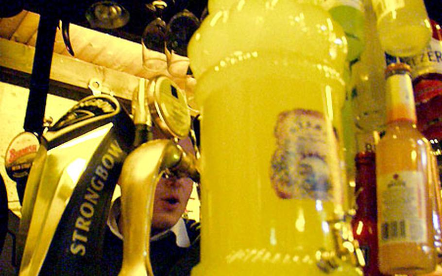 A giant bottle of limoncello dwarfs bottles of American alcohol. Limoncello can be bought in a variety of sizes and bottles.