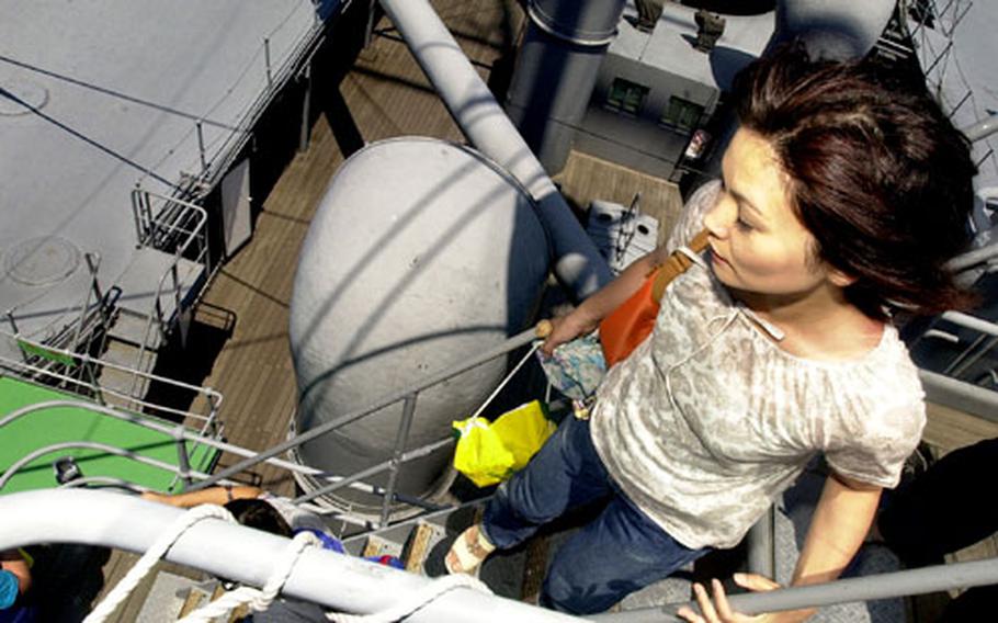 A Japanese visitor attempts to get a bird&#39;s-eye view of Yokosuka city from the mast of the Mikasa.