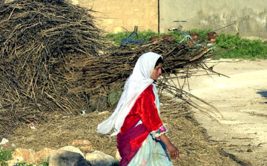 A woman carries hay in the ancient town of Harran, where people still live in primitive mud huts.
