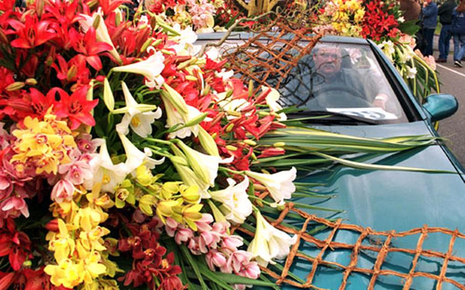 One of the many private cars in the parade is showered with lilies and orchids.