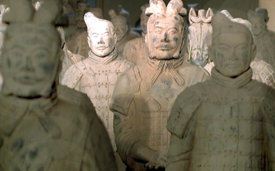 The rank of each terra cotta soldier can be discerned by his hairstyle and uniform. Horses stand among the silent troops.