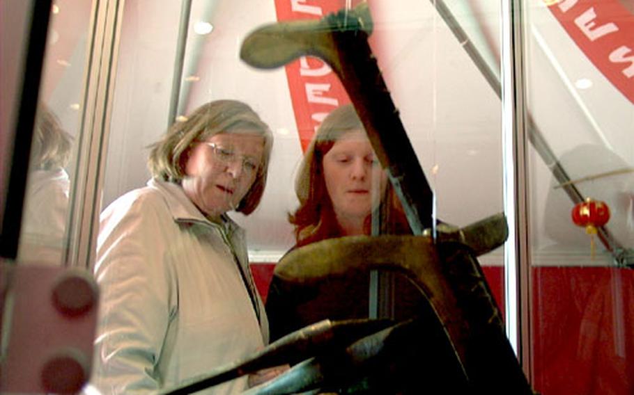 Two visitors gaze into a glass case of ancient weapons.