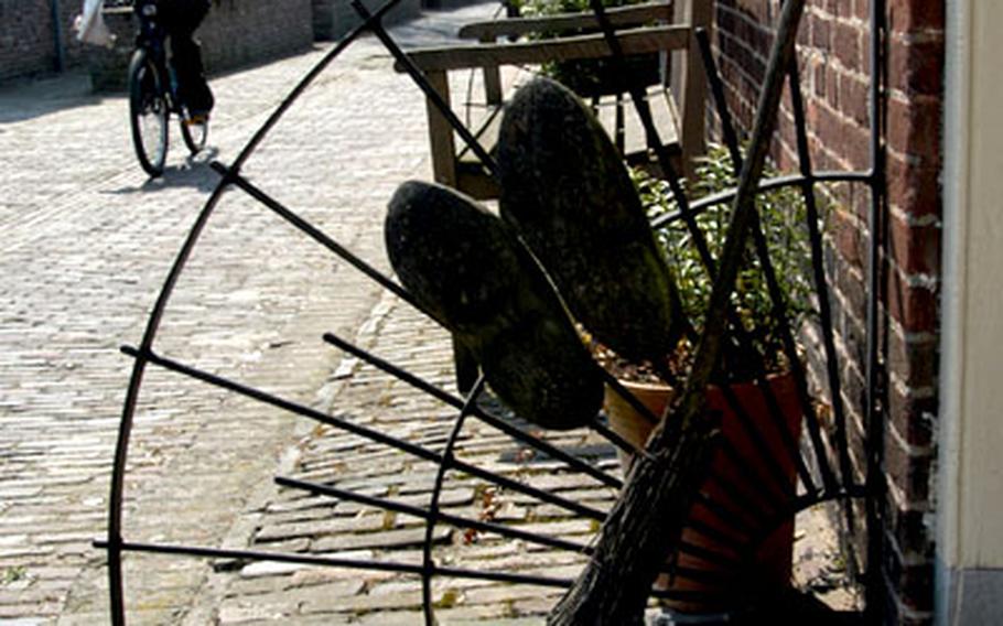 A pair of old wooden shoes and a broom decorate a doorway on one of Woudrichem’s typical cobblestone lanes.