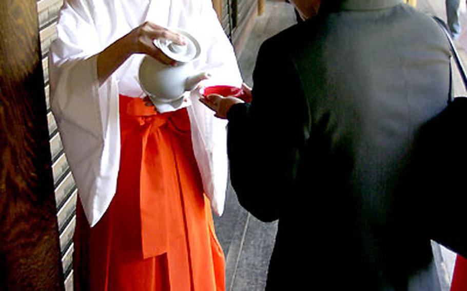 A woman pours sake as an offering to the spirits of those killed in war during the Great Spring Festival.